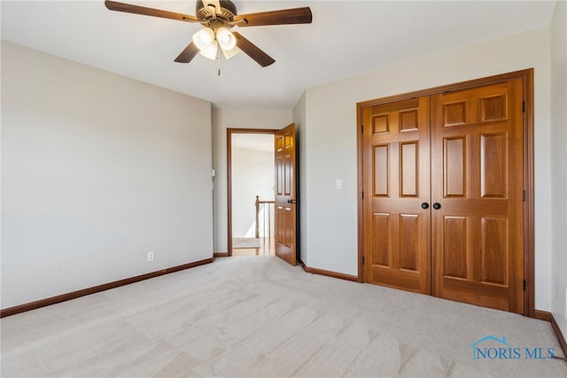 unfurnished bedroom featuring carpet floors, a ceiling fan, baseboards, and a closet