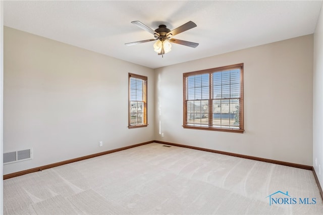 empty room featuring light colored carpet, visible vents, ceiling fan, and baseboards