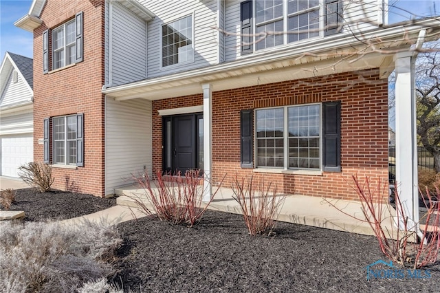 property entrance with covered porch and brick siding