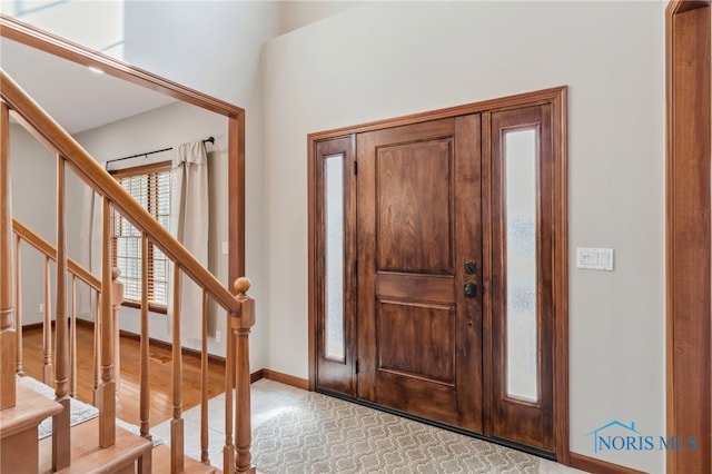 entryway with stairway, baseboards, and light wood finished floors