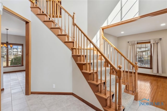 stairway featuring recessed lighting, a high ceiling, baseboards, and an inviting chandelier