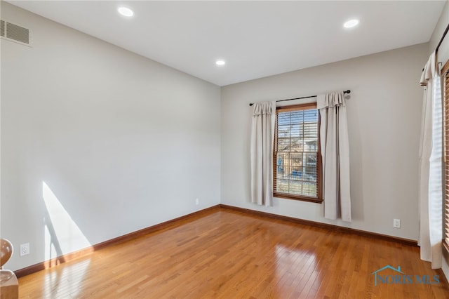 spare room featuring hardwood / wood-style flooring, baseboards, visible vents, and recessed lighting