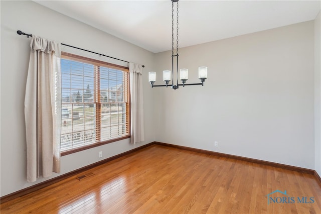 unfurnished room with light wood-type flooring, visible vents, baseboards, and a chandelier