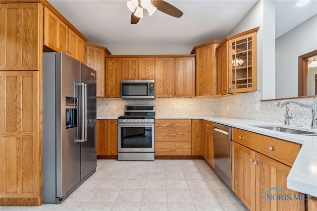 kitchen featuring stainless steel appliances, brown cabinetry, light countertops, and a sink