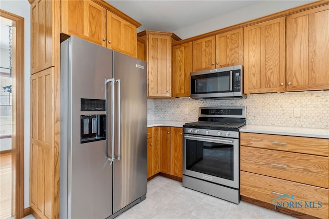 kitchen with appliances with stainless steel finishes, brown cabinets, light countertops, and backsplash