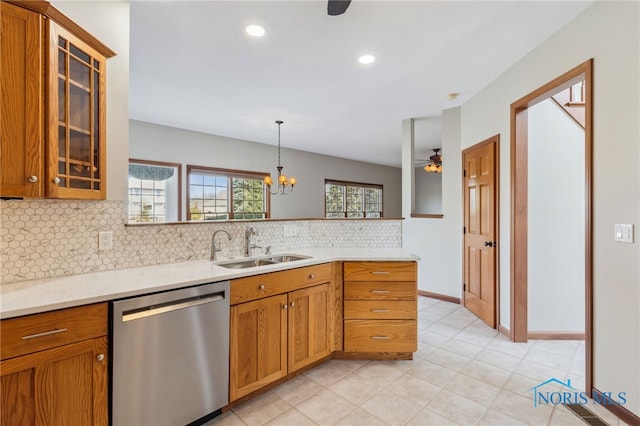 kitchen with light countertops, glass insert cabinets, a sink, dishwasher, and a peninsula