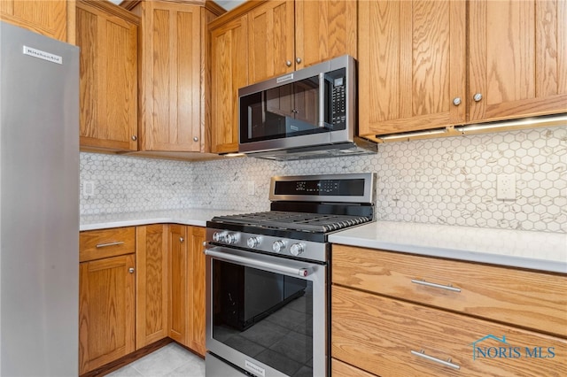 kitchen featuring stainless steel appliances, backsplash, light countertops, and brown cabinets