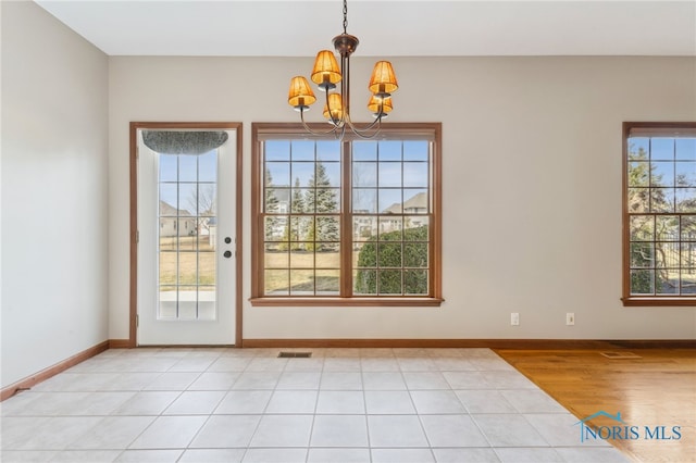 interior space with light wood-style floors, visible vents, baseboards, and a notable chandelier