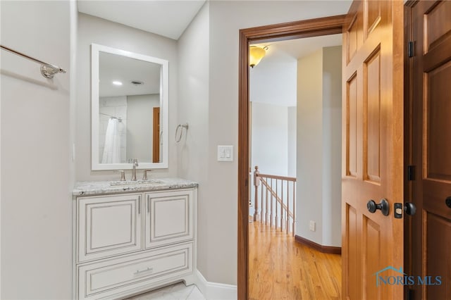 full bathroom with baseboards, wood finished floors, and vanity