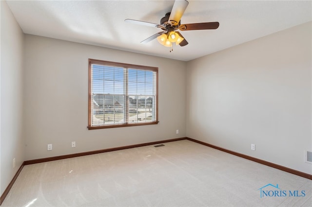 carpeted spare room featuring ceiling fan, visible vents, and baseboards