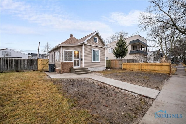 bungalow featuring fence private yard, a chimney, and a front lawn