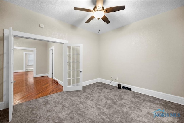 carpeted empty room featuring ceiling fan, baseboards, and a textured ceiling