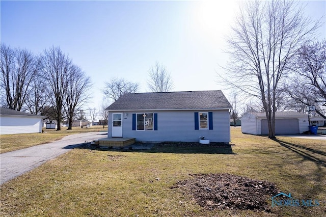 view of front of house featuring a detached garage, an outbuilding, and a front yard