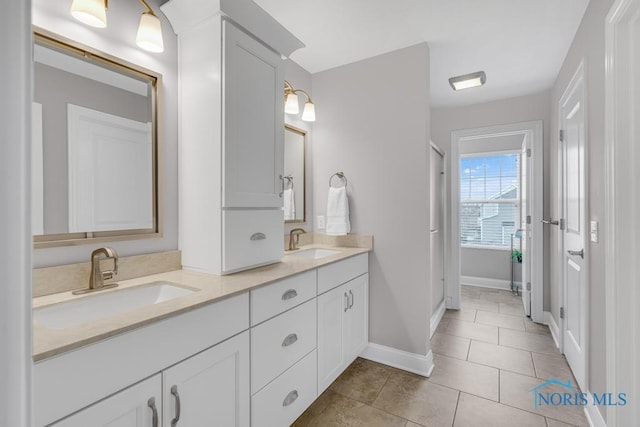 bathroom featuring double vanity, baseboards, a sink, and tile patterned floors