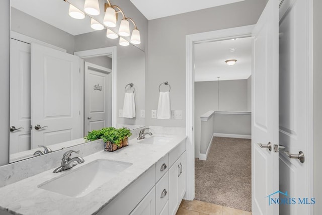 full bath featuring double vanity, tile patterned flooring, a sink, and baseboards