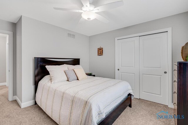 bedroom featuring a closet, visible vents, a ceiling fan, light carpet, and baseboards