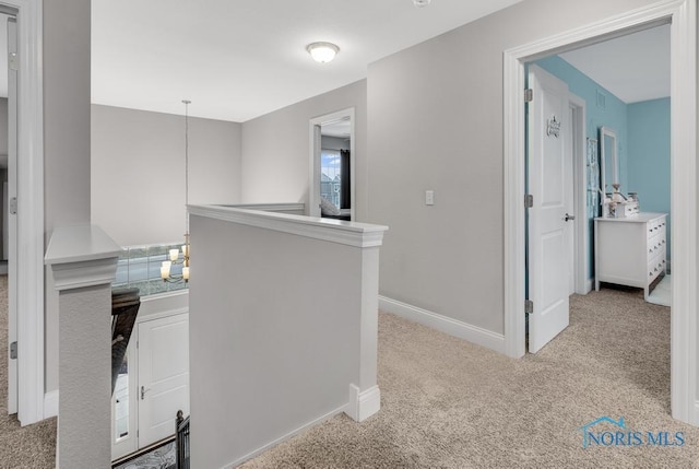 hallway featuring a notable chandelier, carpet floors, an upstairs landing, and baseboards