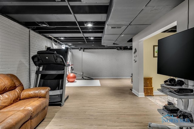 workout area featuring brick wall, wood finished floors, and visible vents