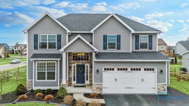 view of front of home with a garage, stone siding, aphalt driveway, and fence