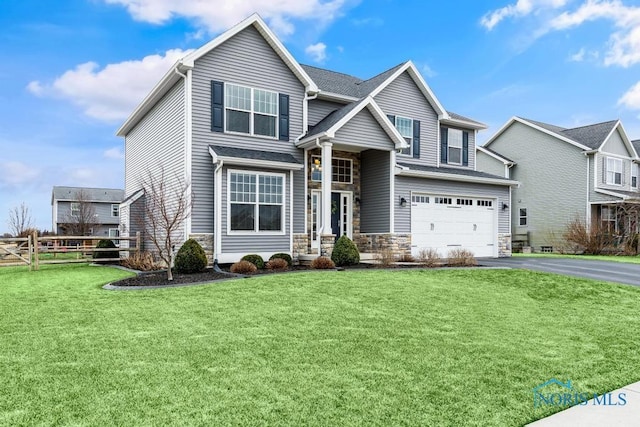 craftsman-style house featuring an attached garage, a front yard, fence, stone siding, and driveway