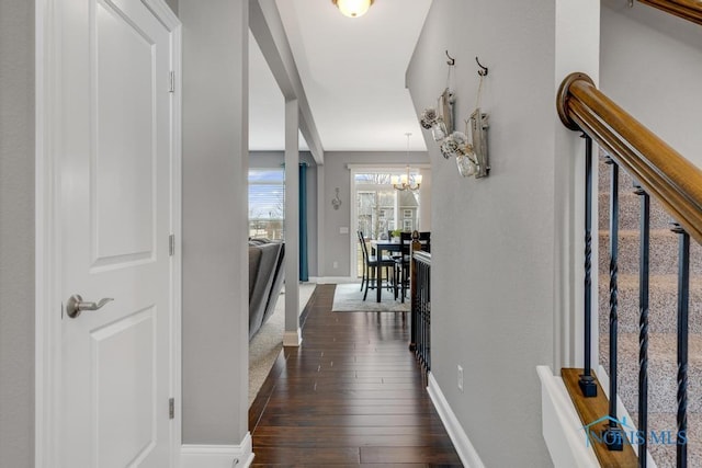 corridor with baseboards, stairway, dark wood finished floors, and an inviting chandelier