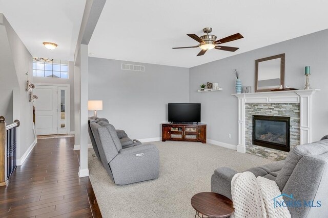 living area with baseboards, visible vents, dark wood finished floors, ceiling fan, and a fireplace