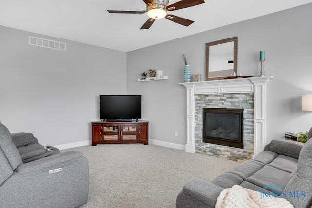 living area featuring ceiling fan, a stone fireplace, carpet floors, visible vents, and baseboards