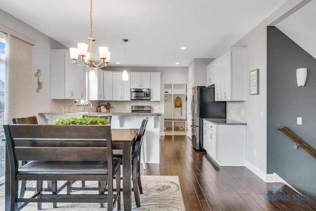 dining area with an inviting chandelier, baseboards, dark wood-style flooring, and recessed lighting