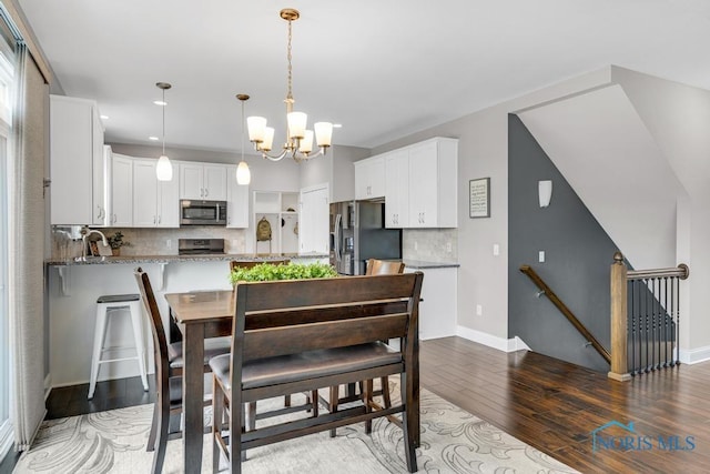 dining area with wood-type flooring, a chandelier, and baseboards