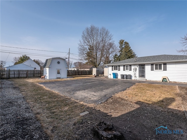 back of property featuring a storage shed, an outdoor structure, and fence