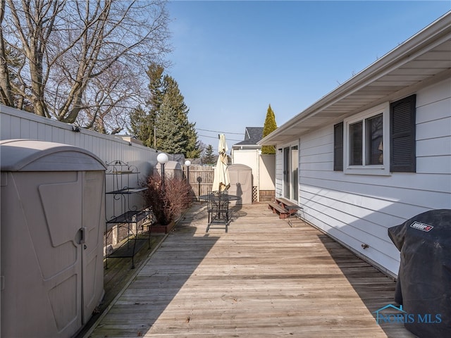 wooden deck featuring a grill, fence, and outdoor dining space