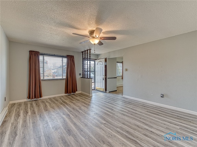 unfurnished room featuring baseboards, a textured ceiling, a ceiling fan, and wood finished floors