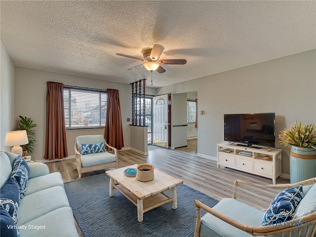 living room with baseboards, a textured ceiling, a ceiling fan, and wood finished floors