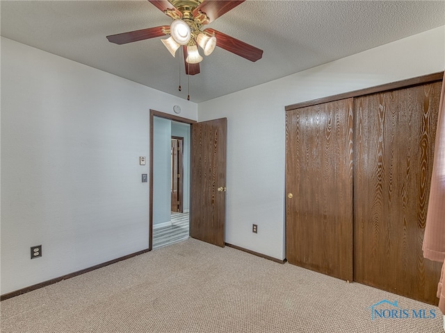 unfurnished bedroom with a textured ceiling, carpet floors, a ceiling fan, baseboards, and a closet