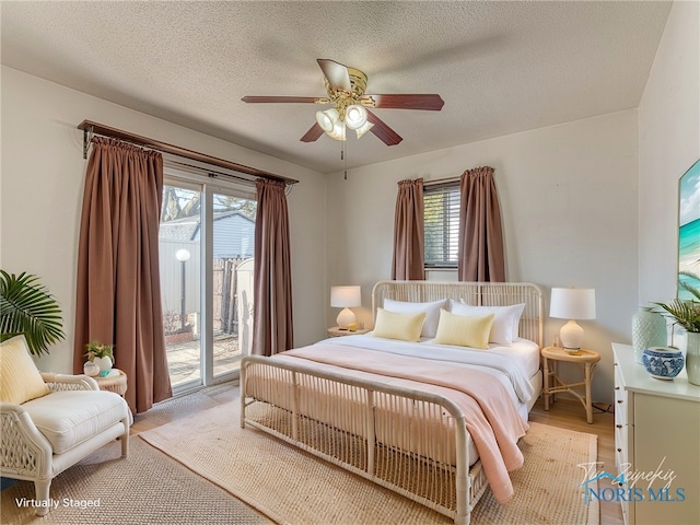 bedroom featuring access to exterior, ceiling fan, light wood-style flooring, and a textured ceiling