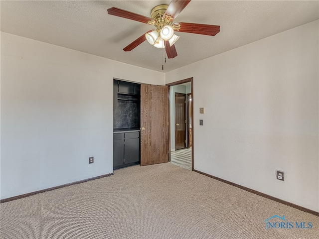 unfurnished bedroom featuring light carpet, baseboards, ceiling fan, a textured ceiling, and a closet