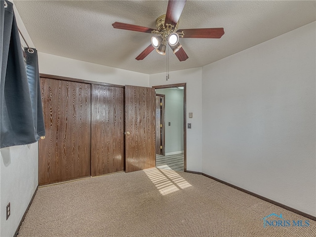 unfurnished bedroom with carpet, a closet, baseboards, and a textured ceiling