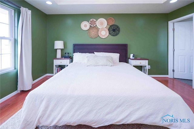 bedroom with baseboards, wood finished floors, and recessed lighting