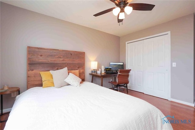 bedroom with a closet, wood finished floors, a ceiling fan, and baseboards