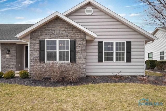 exterior space featuring stone siding and a front yard