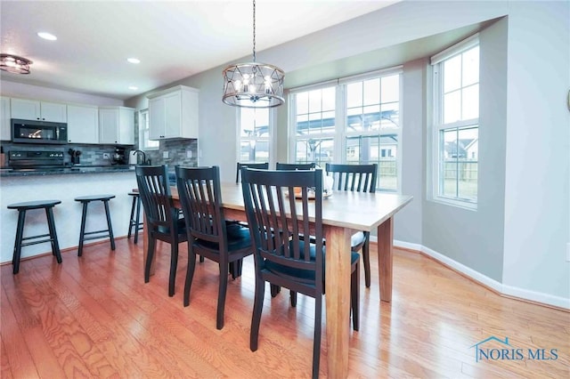 dining space with a chandelier, recessed lighting, light wood-style flooring, and baseboards