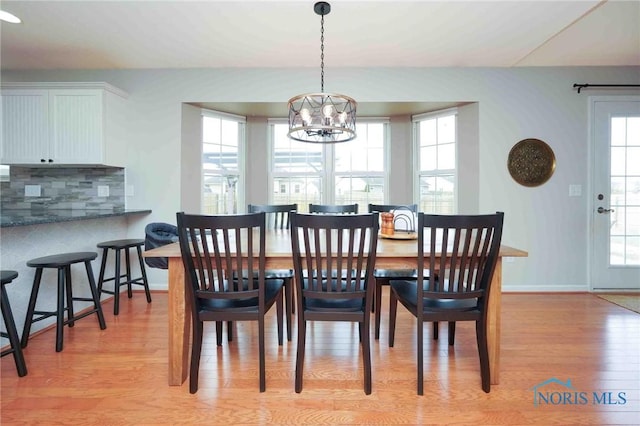 dining room featuring baseboards, a notable chandelier, and light wood finished floors