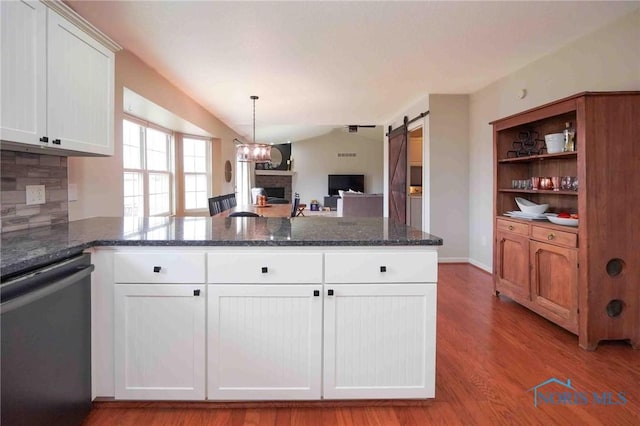 kitchen featuring a barn door, wood finished floors, white cabinetry, open floor plan, and dishwasher