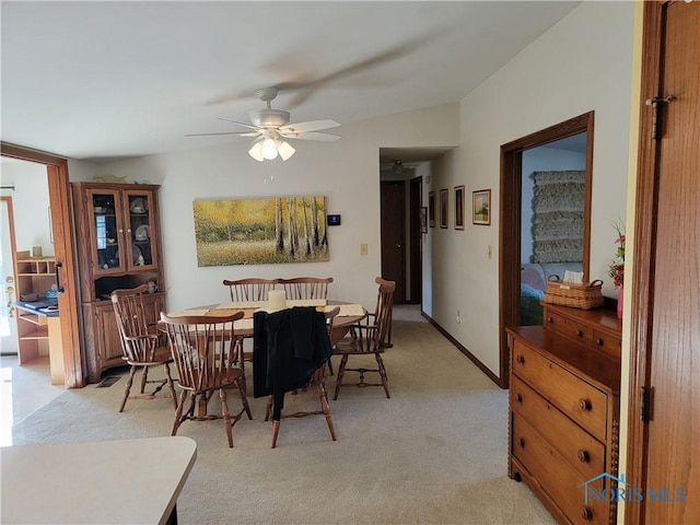 dining space featuring ceiling fan, baseboards, and light colored carpet