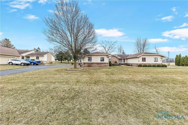 ranch-style home with aphalt driveway and a front yard