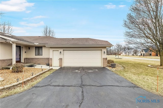 view of front facade with a garage, a front yard, brick siding, and driveway