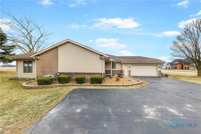 ranch-style home featuring an attached garage, a front lawn, aphalt driveway, and brick siding