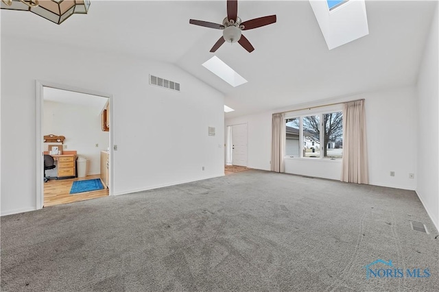 unfurnished living room featuring a skylight, carpet, visible vents, and a ceiling fan