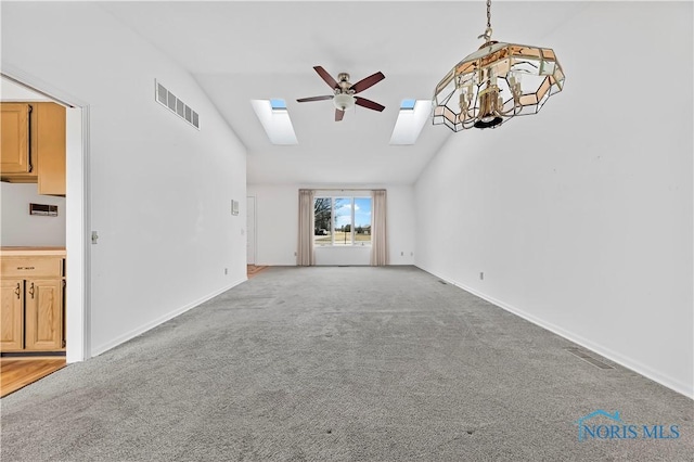 unfurnished living room with vaulted ceiling with skylight, visible vents, and light colored carpet