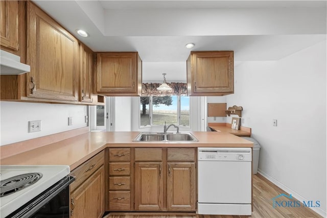 kitchen with light wood finished floors, light countertops, a sink, white appliances, and baseboards